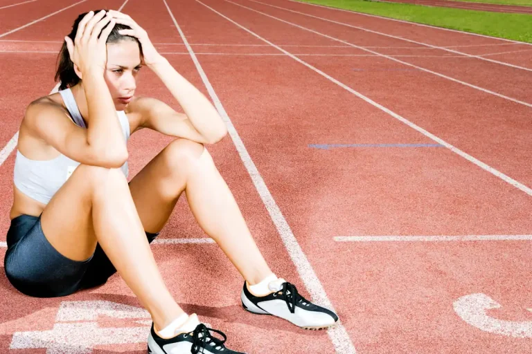 Une femme qui se tient la tête assise sur une piste de course