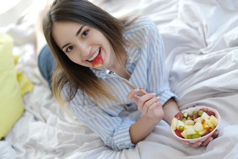 Une femme qui mange une assiette de fruits